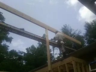 Carpenter setting a ridge beam over a new addition frame — Ice Dam Removal by Roofing Brothers in Navasota