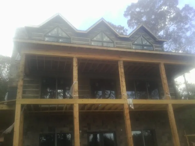 Dormers and porch framing on a large log home under construction — Roof Coating work by our crew in Navasota
