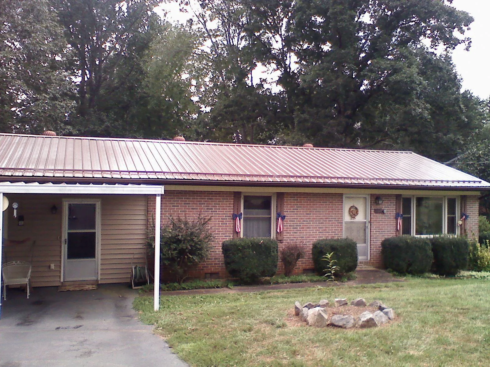 Bronze metal roof and carport on a brick ranch home — Roof Repair work by our crew in Navasota