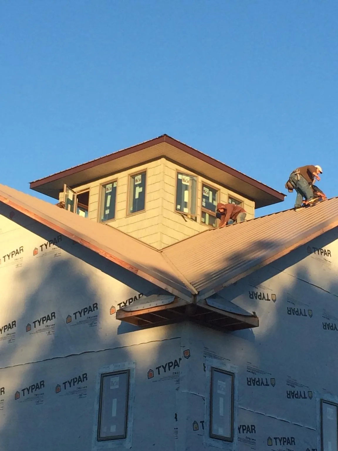 Roofers working around a rooftop cupola on a new metal roof at sunset — Roof Waterproofing in Navasota by Roofing Brothers